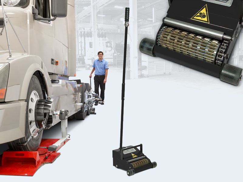 White truck on Hunter alignment platform with technician and control panel in professional service garage.